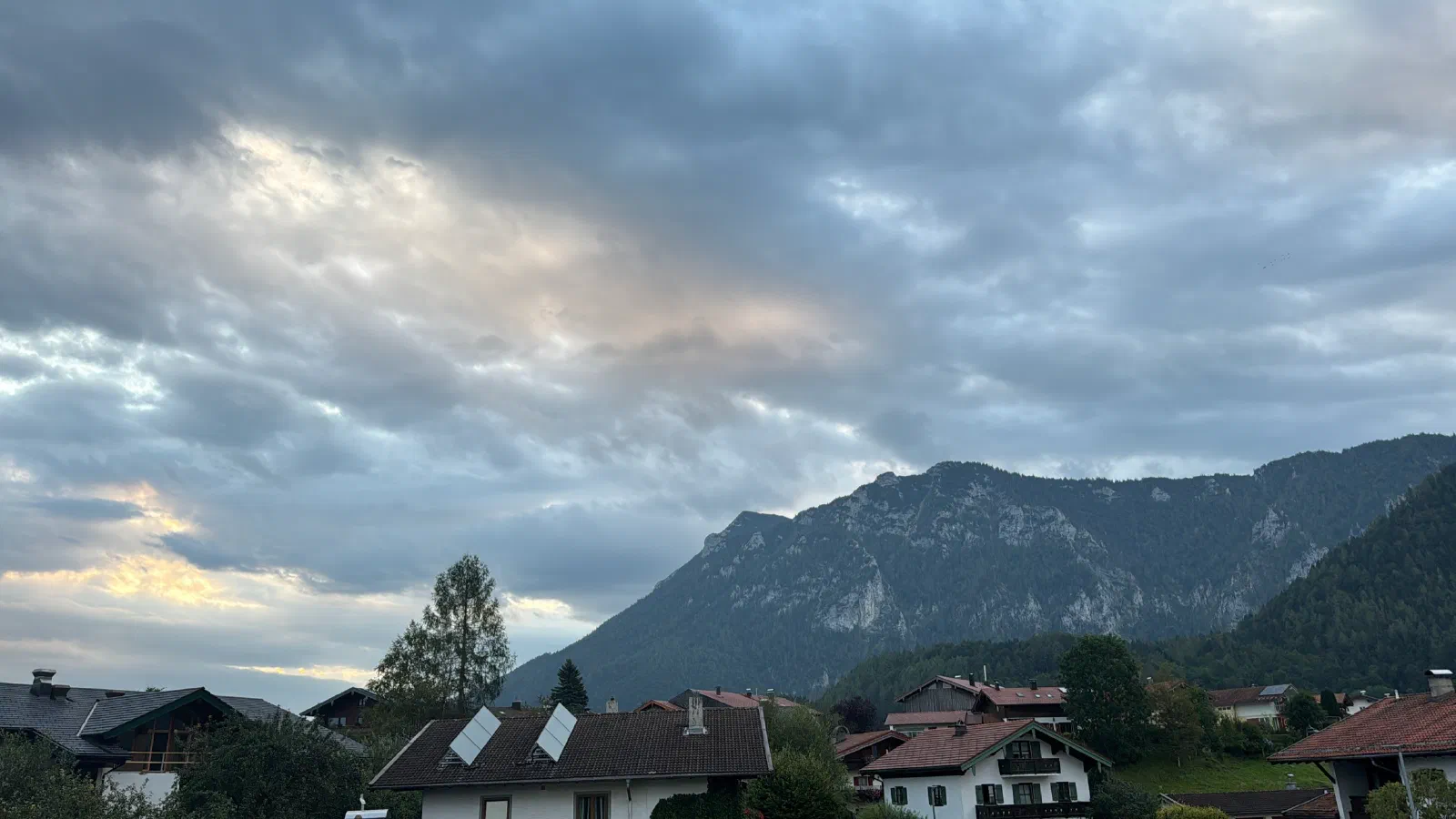 Houses in Inzell in front of a mountain massif under gray clouds